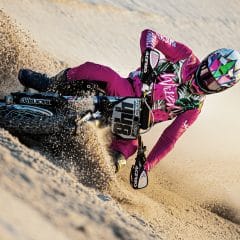 Dirt bike rider in pink mx gear riding in the sand